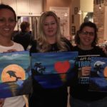 paint night guests showing off their completed works of art