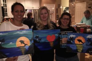 paint night guests showing off their completed works of art
