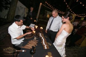 Guests watching a cigar roller create hand-made cigars for them at a party.