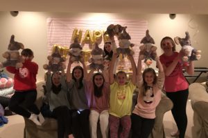Happy girls holding up their fill-a-friend stuffed animals after making them at a party.