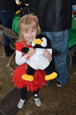 Young girl with penguin fill-a-friend, stuffed animal for a child's party.