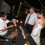 Guests watching a cigar roller create hand-made cigars for them at a party.